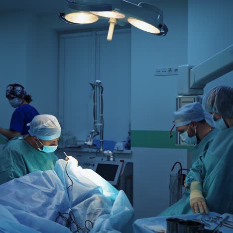 medical team in the operating room. surgeon performing blepharoplasty to a patient under the medical lamp. group of doctors doing plastic surgery.