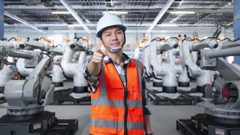 ingeniero apuntando a brazos robóticos en una fábrica