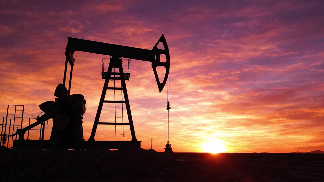 Sunset Over an Oil Pump Jack: A Striking Silhouette Against a Vibrant Sky Illuminated by Warm Colors of Dusk
