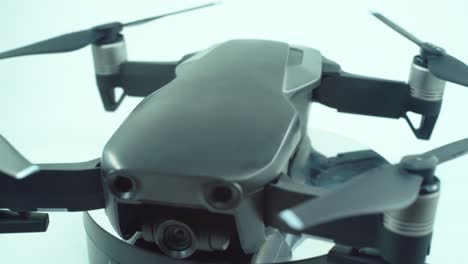 close up shot of a drone with camera lens and propellers, silver grey color, on a rotating 360 stand, slow motion, 4k video