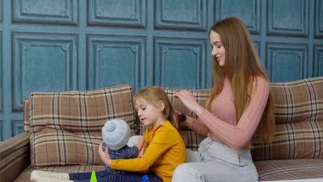 Mutter-Kümmert-Sich-Um-Tochter,-Mädchen-Bürstet-Haare-Im-Wohnzimmer,-Kind-Spielt-Mit-Spielzeugpuppe