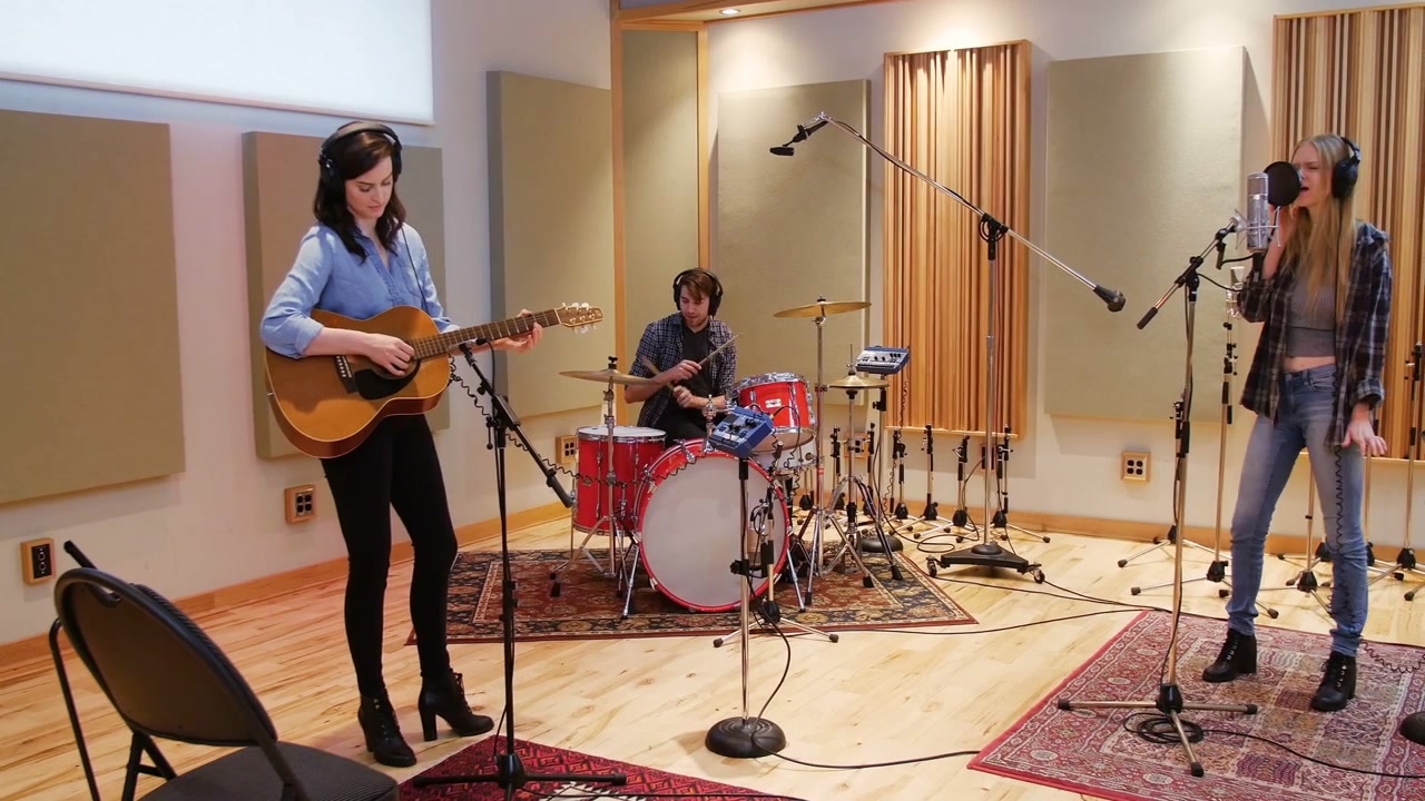Trio che si esibisce in studio, musica che provoca bolle CTA che spuntano dai bordi e coprono la parte inferiore del fotogramma.