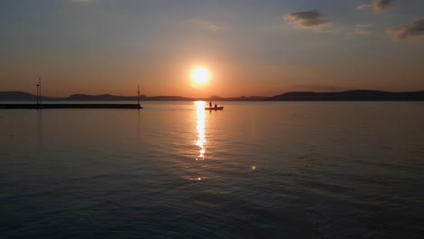 Un-Pequeño-Barco-Perfilado-Durante-La-Hermosa-Puesta-De-Sol-Se-Mueve-Lentamente-En-Un-Puerto-Tranquilo