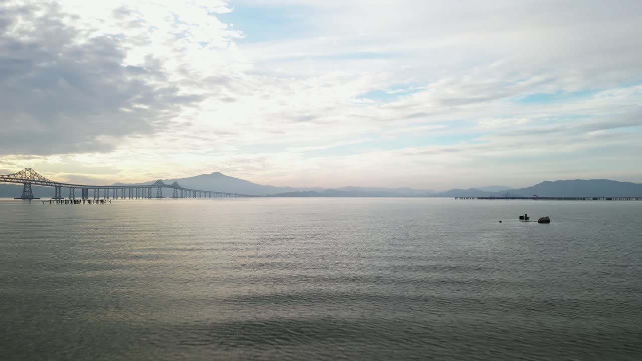 Low aerial dolly rises above ripples in water to Richmond Bridge from Point Molate Beach Richmond California USA