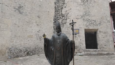 tilt up of catholic priest or pope holding staff with crucifixion in courtyard, cartagena