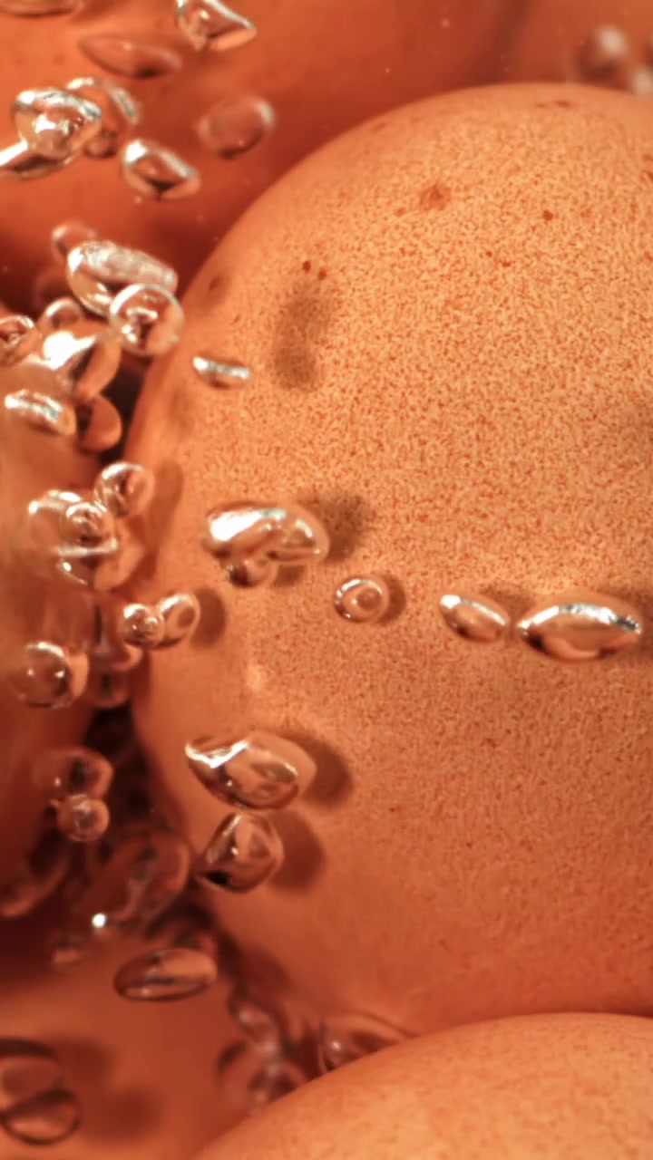 Primo piano di uova marroni che bollono in acqua con bolle