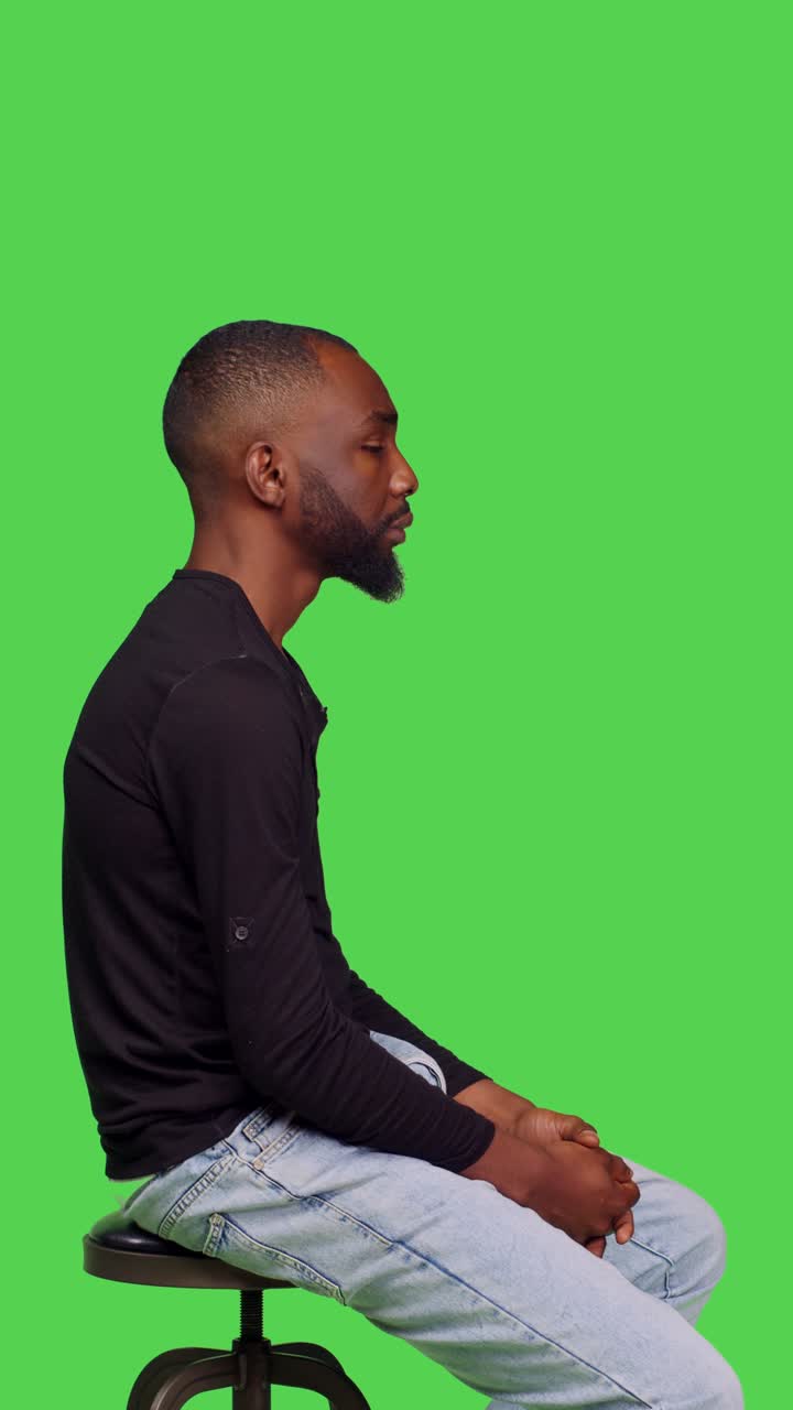 Vertical video: Profile of african american guy sitting on chair and waiting