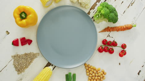 video of fresh vegetables arranged around grey plate with copy space on white rustic background