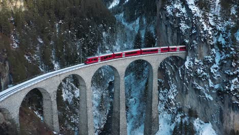 excellent aerial view of a train coming out of the landwasser viaduct in switzerland