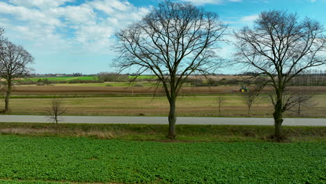 a view from the edge of a field with two bare trees framing the scene