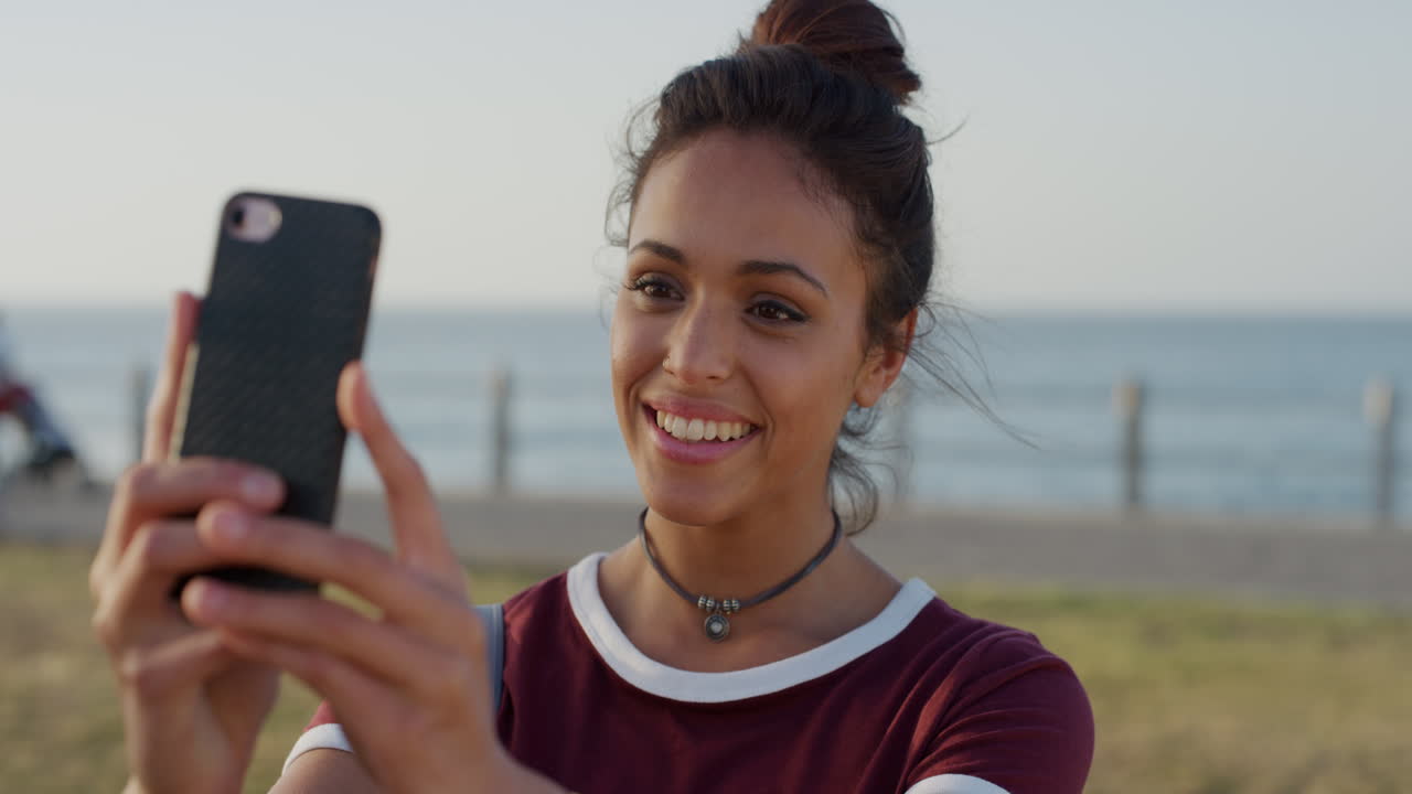 retrato atractiva joven mujer hispana turista usando un teléfono inteligente tomando una foto selfie disfrutando de hermosas vacaciones soleadas en la orilla del océano compartiendo experiencia