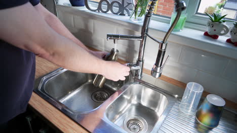 llenar la botella de agua del grifo y enroscar la tapa de la tapa en la mano masculina