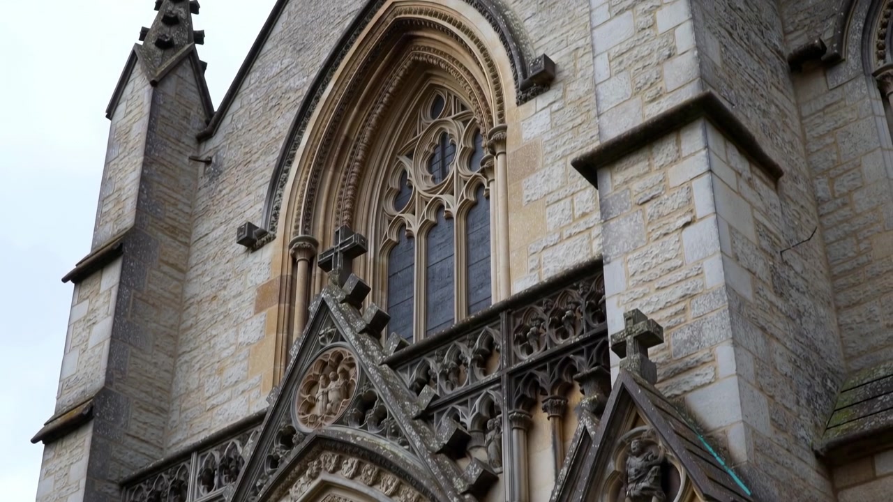 Primo piano della facciata di una cattedrale gotica che mostra intagli in pietra intricati e trafori, finestra ad arco con montanti.