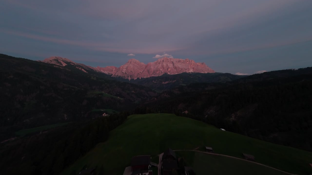 Riprese aeree al tramonto della valle vicino a Ortisei, Italia, con le Dolomiti sullo sfondo e luce calante.