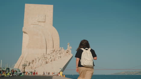 woman walking towards the monument to the discoveries in lisbon, portugal