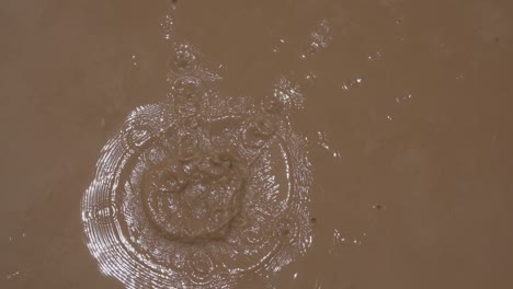 stone falling to muddy water puddle in slow-motion
