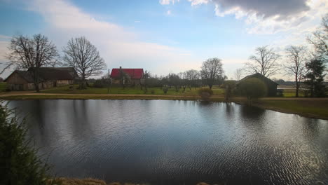 timelapse of reflections of a village pond and sunrise light over cottages and trees