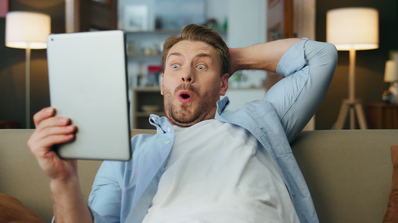 타블 화면을 실내에서 지켜보는  놀란 남자. 흥분한 남자가 입을 열고