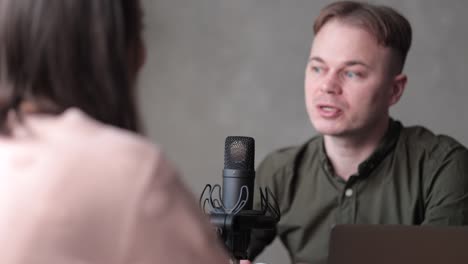 couple of male and female radio hosts or podcasters speak into a microphone with headphones create audio content in the studio or on the radio on the air