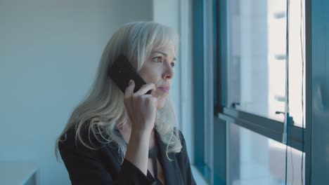 focused middle aged business lady standing near window