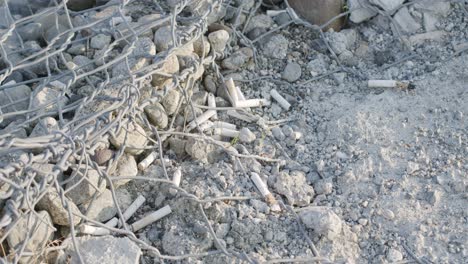 Cigarette-butts-thrown-out,-in-a-rock-cage