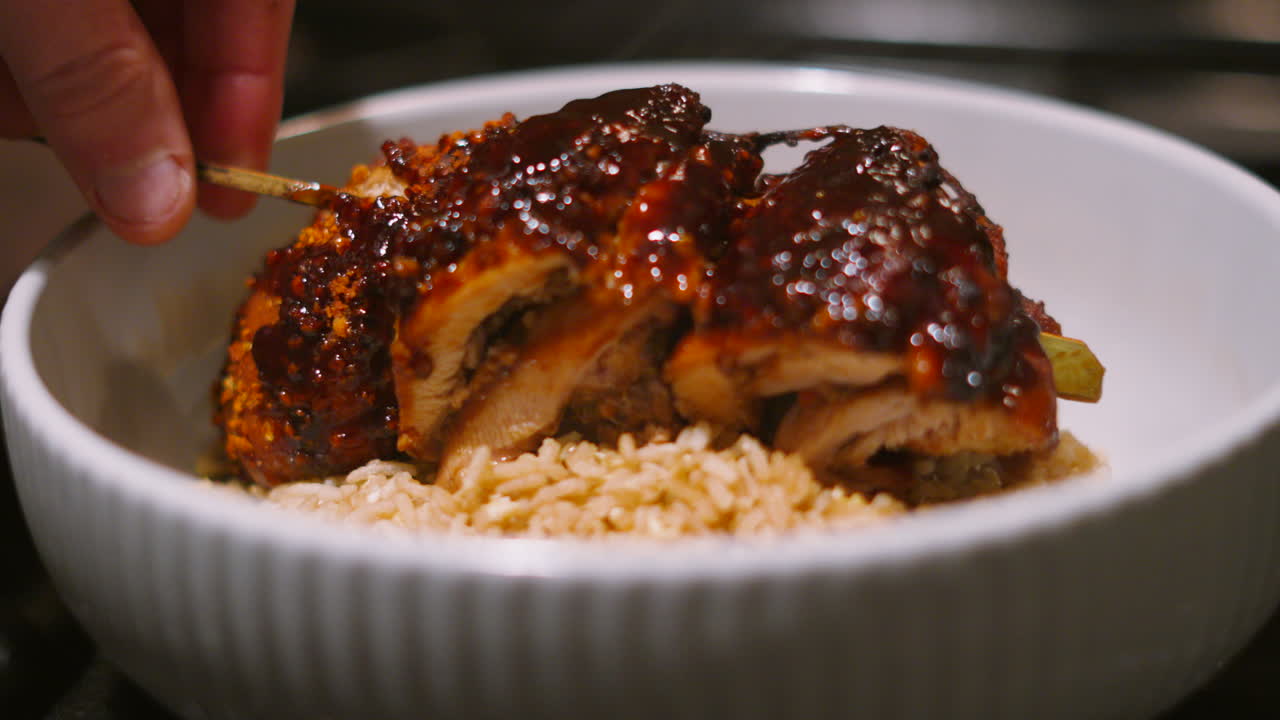 Japan Teriyaki Miso Chicken King Kebab Being Gently Lowered onto Bed of Egg Fried Rice Ready to Serve Hot Steam Rising from Freshly Cooked Meat Covered in Sweet Sticky Sauce. Japanese Cuisine 4K.