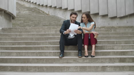 Smiling-coworkers-looking-good-work-results-on-documents-in-modern-city