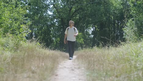 young man walking with guitar on street near forest