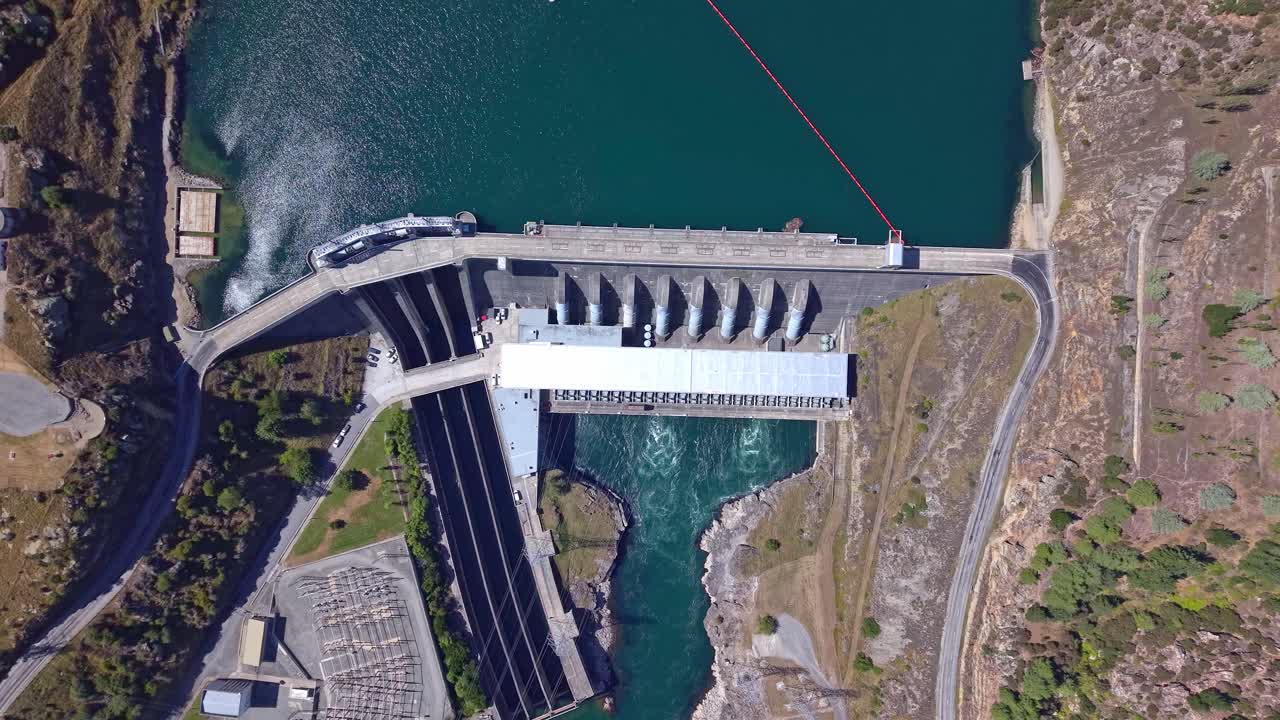 Drone flying in reverse and rising upward, starting from an upper close view of Roxburgh Dam and unzooming to reveal the full hydro structure in Central Otago, New Zealand