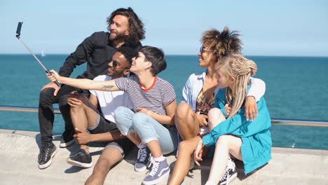 laughing friends taking selfie on seafront