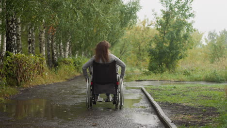 woman with paralysis moves in park with puddles on windy day