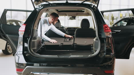 customer checking back seat of a black suv in a car showroom