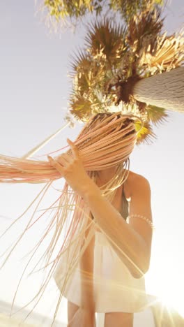 woman with blonde braids under palm tree