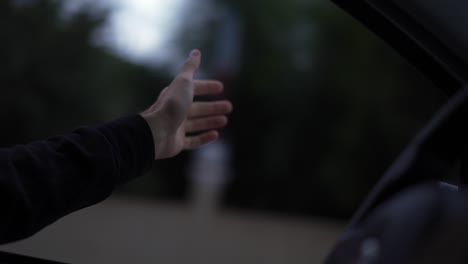 a man's hand is catching the wind while driving a car on a rainy day