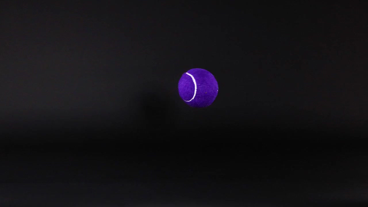 Tennis ball bouncing against a dark background