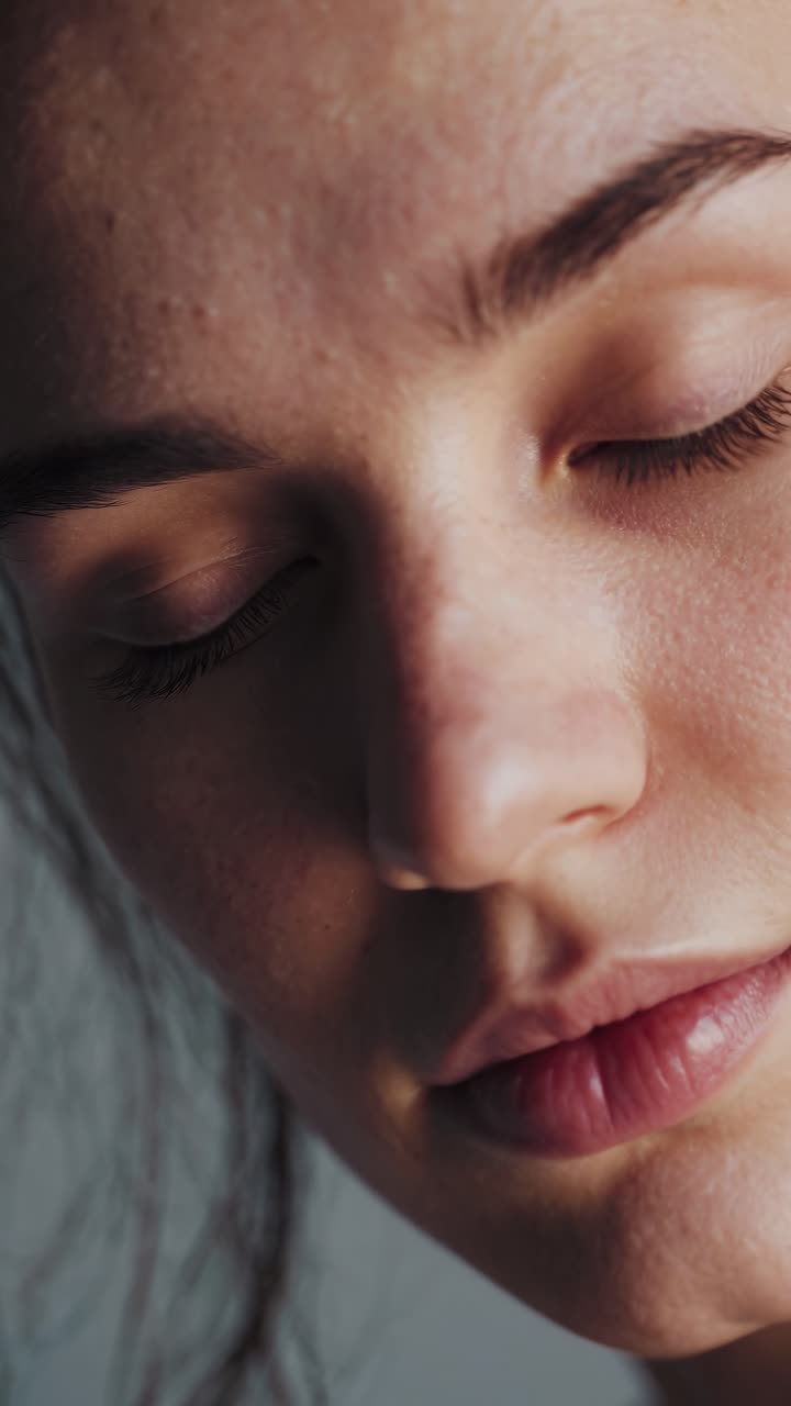 Close-up shot of a woman's serene face with closed eyes, capturing natural skin texture