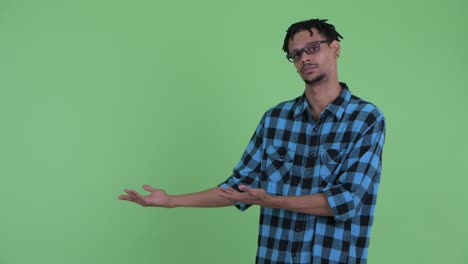 joven y guapo hombre africano hipster mostrando algo