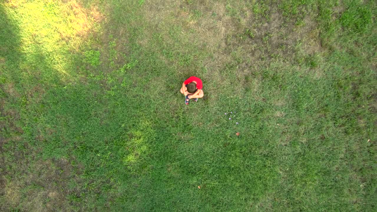 들판 한가운데에 혼자 앉아 있는 어린 소년, 슬의 개념, 공중 풍경.