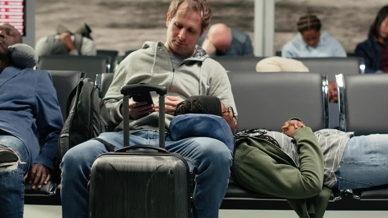 Sleeping on chairs, departure board screen and tourists tired in airport