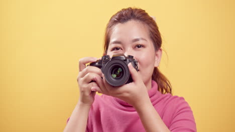 광고용 복사 공간이 있는 디지털 카메라를 사용하여 격리된 노란색 배경 위에 촬영된 스튜디오의 아시아의 멋진 젊은 여성-1