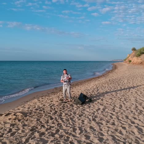 beautiful sea coast under blue sky. musician is singing on empty beach with hills near the blue water. motion camera back