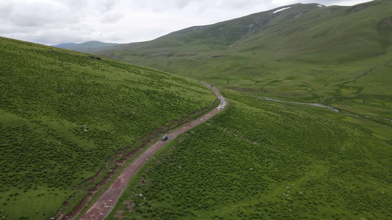 длинная сельская дорога пересекает обширные зеленые поля и холмы