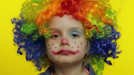 little child girl clown in colorful wig tells something interesting. having fun, smiling. halloween