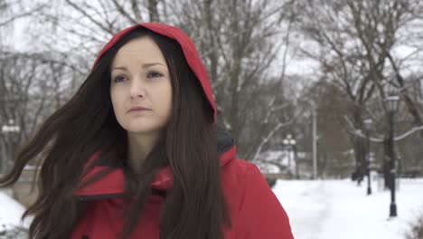 lovely caucasian woman in hoodie coat walks in the snowed city park during winter