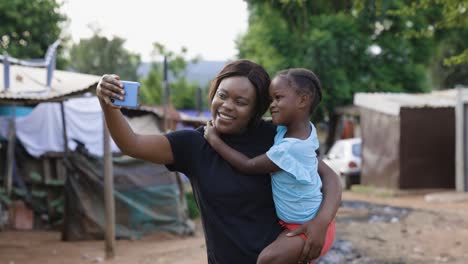 black african lesbian woman with her cute daughter taking a selfie in an informal settlement slum