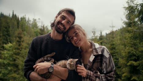 Happy-couple:-a-guy-and-a-girl-are-posing-and-smiling,-they-are-standing-on-a-balcony-overlooking-a-coniferous-forest-in-the-mountains