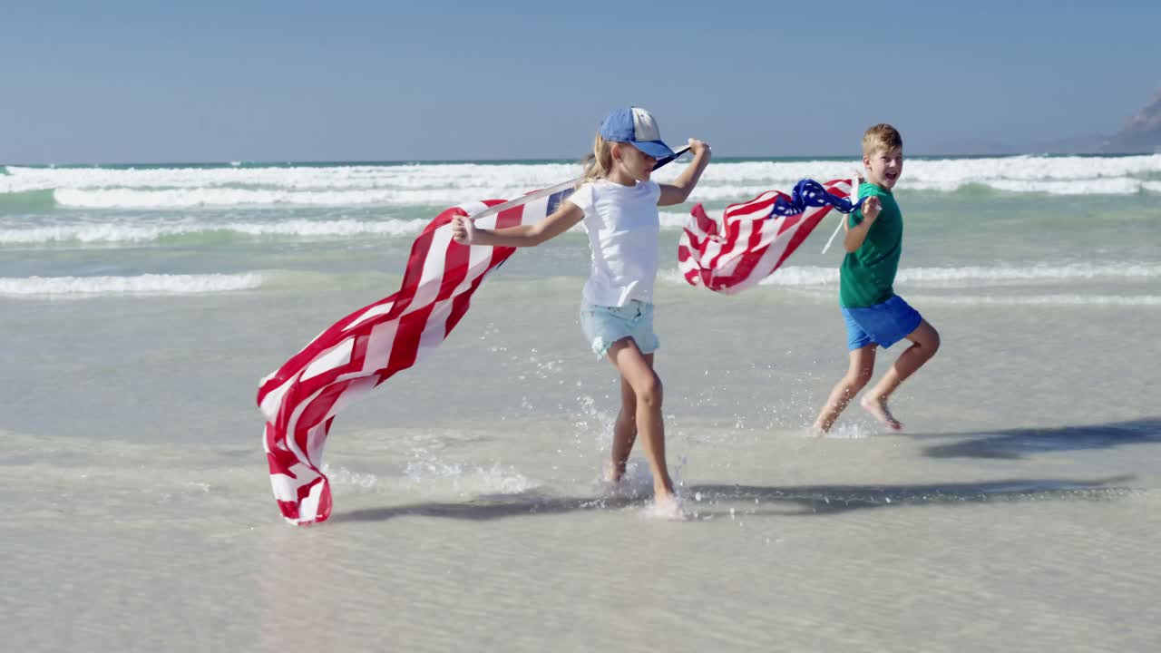 hermanos sosteniendo la bandera estadounidense mientras corren en la orilla en la playa