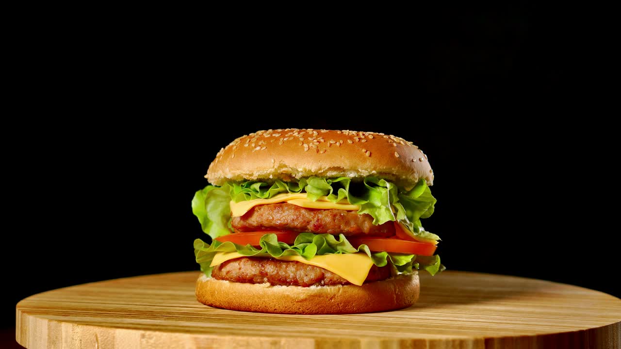 hamburguesa fresca y apetitosa girando sobre un fondo negro.