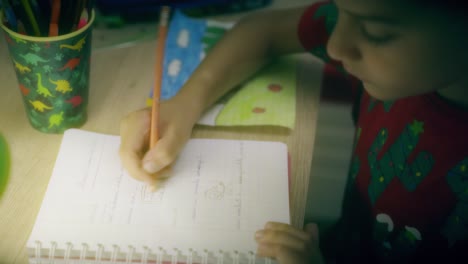 child-drawing-at-night-on-his-desk-and-coloring-with-colored-paints