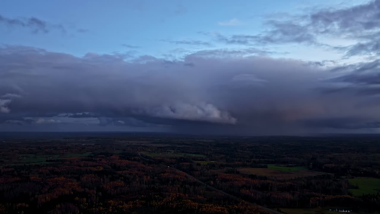 Timelapse of dense storm clouds sweeping across a rural landscape at dusk